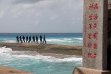 Soldiers of China's People's Liberation Army (PLA) Navy patrol near a sign in the Spratly Islands, known in China as the Nansha Islands, February 9, 2016. The sign reads 'Nansha is our national land, sacred and inviolable.' PHOTO BY REUTERS/Stringer