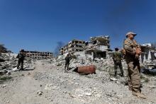 Members of Syrian forces of President Bashar al Assad stand guard near destroyed buildings in Jobar, eastern Ghouta, in Damascus, Syria, April 2, 2018. PHOTO BY REUTERS/Omar Sanadiki
