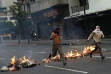 Opposition students run from police and past burning trash as they protest against President Nicolas Maduro's government in Caracas, February 12, 2015. PHOTO BY REUTERS/Jorge Silva