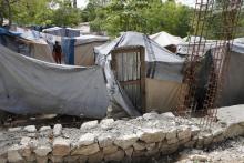 A woman made homeless by the 2010 earthquake, walks between tents as a wall (foreground) is being built by the owners of the land where she lives in Shelter Camp 3, one of 385 informal 'tent cities' still existing since the disaster, in the Delmas suburb of Port-au-Prince, April 22, 2013. PHOTO BY REUTERS/Marie Arago