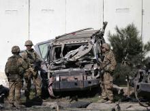 U.S. troops keep watch near a damaged vehicle at the site of suicide attack in Kabul