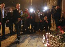 Russian president Vladimir Putin puts flowers down outside Tekhnologicheskiy Institut metro station in St. Petersburg, Russia. PHOTO BY REUTERS/Grigory Duko