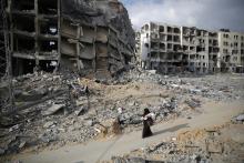 A Palestinian woman walks past buildings destroyed by what police said were Israeli air strikes and shelling in the town of Beit Lahiya in the northern Gaza Strip