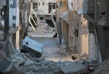 A woman sits amid damaged buildings in the rebel-held al-Myassar neighborhood of Aleppo, Syria. PHOTO BY REUTERS/Abdalrhman Ismail