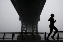 A woman is seen silhouetted while running under the fog covered Manhattan Bridge in New York, December 14, 2015. PHOTO BY REUTERS/Shannon Stapleton