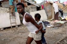 A woman carries a child as they walk in front of destroyed houses after Hurricane Matthew passes Jeremie, Haiti, October 7, 2016. PHOTO BY REUTERS/Carlos Garcia Rawlins