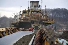 A worker observes a man picking coal from the conveyor of coal mine in Zivinice near Tuzla