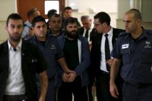 Yosef Haim Ben-David, (C) who was convicted of murdering a Palestinian teenager in Jerusalem, is led into the courtroom by Israeli prison guards at Jerusalem's District Court, April 19, 2016. PHOTO BY REUTERS/Ammar Awad
